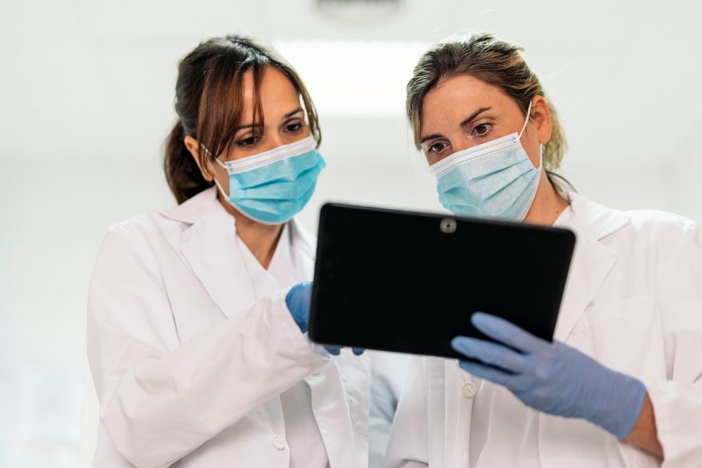 Two doctors discussing treatment while looking at a tablet.