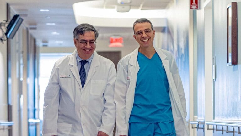 Two Cooper and Inspira doctors walking and smiling in a hospital hall.